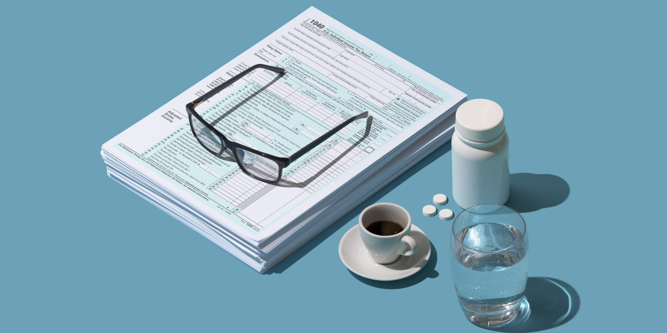 Filing taxes is stressful: pile of tax forms, coffee and calming pills